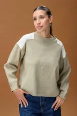 Sweater de punto color beige con cuello redondo y detalles de parches en cuero sintético blanco en los hombros. Presenta mangas largas con puños acanalados y un corte holgado.