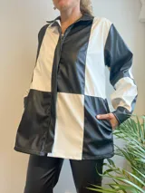 Campera con cierre frontal, diseño color block blanco y negro, cuello camisero y bolsillos laterales.