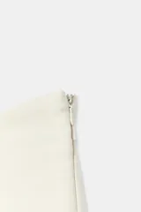 Falda pantalón de tiro bajo color blanco crudo, con diseño de cintura asimétrica y cierre lateral con cremallera oculta en costura.