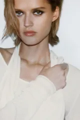 Camiseta de manga larga color crudo con cuello redondo y detalle de top halter superpuesto en el mismo tejido. Presenta un diseño de doble capa con caída drapeada en el frente.