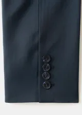 Blazer negro de corte recto con solapas de muesca, cierre frontal de un botón, bolsillos con solapa en los laterales y un bolsillo de ribete en el pecho.