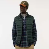 Chaleco tipo puffer de color verde oscuro, con cierre frontal completo, cuello alto y diseño acolchado horizontal.