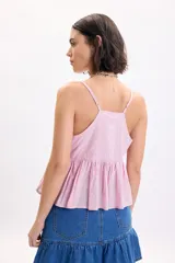 Top sin mangas lila con diseño de broderie, escote en V y detalle de botones frontales decorativos. Presenta tirantes finos regulables y corte peplum fluido.