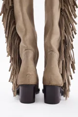 Bota bucanera de caña alta confeccionada en cuero vacuno, con diseño de estilo western que presenta flecos laterales largos y taco cuadrado.