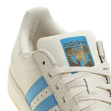 Championes Adidas Superstar edición especial Messi, color crema con las icónicas tres tiras en azul celeste. Presenta el logo de Messi grabado en el lateral y en el talón, con la clásica puntera de goma y suela de color goma.