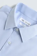 Camisa de corte slim fit confeccionada en tejido de algodón, con cuello italiano, manga larga con puños abotonados y cierre frontal de botones.