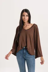 Blusa negra de tela con lycra, escote en V y mangas anchas.