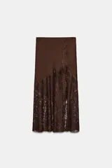 Falda midi de tiro alto confeccionada en tejido satinado color marrón. Presenta un diseño evasé con aplicación de encaje en el lateral y el bajo, y cierre lateral con cremallera oculta.