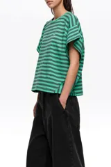 Remera corta de corte amplio confeccionada en 100% algodón, con diseño a rayas horizontales azules y negras, escote redondo, mangas cortas caídas y pequeño logo bordado en el pecho.