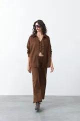 Sobrecamisa de gamuza color marrón, de silueta relajada, con cuello camisero, botones frontales y bolsillos de parche en el pecho.