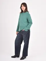 Buzo de tejido de punto color negro, con cuello redondo, mangas largas y puños anchos acanalados. Presenta un diseño con ruedo asimétrico y aberturas laterales.