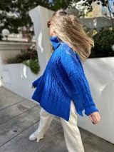 Sweater azul eléctrico de tejido de punto trenzado, cuello alto y corte oversize con aberturas laterales.