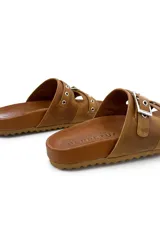 Sandalias de cuero color tostado, con doble tira sobre el empeine, ojales metálicos y hebillas plateadas ajustables.