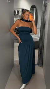 Vestido largo color verde oscuro, de corte strapless con escote recto y falda larga con caída fluida. Incluye una gargantilla a juego.