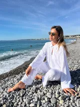 Camisa blanca de broderie con cuello camisero, mangas largas y cierre frontal con botones.