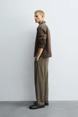 Pantalón regular fit color marrón oscuro, confeccionado en tejido con viscosa. Cuenta con cintura elástica, bolsillos delanteros y detalle de bolsillos traseros de vivo. El cierre frontal es con cremallera y botón.