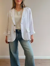 Blazer de lino color beige, de corte relajado y líneas clásicas. Presenta cuello con solapas, cierre frontal con dos botones y bolsillos con solapa en el frente.