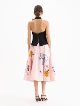 Pollera midi evasé tableada de color rosado, confeccionada en algodón con un estampado de flores y abejas, enriquecido con bordado de mostacillas.