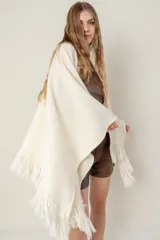 Ruana de lana color beige, tejida en punto acanalado con terminación de flecos en los bordes.