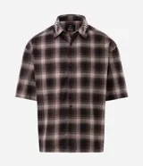 Camisa boxy de manga corta color marrón y negro a cuadros, con cuello camisero que presenta detalle de lettering bordado.