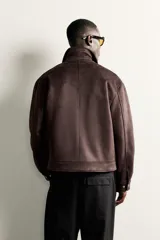 Cazadora de corte regular fit confeccionada en tejido efecto ante, con cuello solapa, cierre frontal con cremallera, bolsillos de vivo en la cadera y mangas largas con puños abotonados.