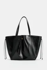 Bolso tipo shopper de efecto arrugado y acabado brillante en color negro, con detalles fruncidos en el centro, cordones colgantes en los laterales y doble asa para el hombro.