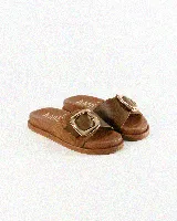 Sandalias de cuero color negro, de diseño plano con una tira ancha en el empeine y una hebilla metálica dorada grande como detalle.