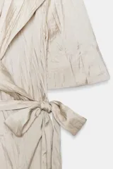 Vestido midi de Zara Woman Collection color beige, con cuello solapa, mangas por debajo del codo y diseño cruzado. Confeccionado en tejido plisado con brillo satinado, incluye un cinturón ajustable del mismo género con lazada en la cintura.