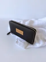 Billetera grande de cuero color negro, con cierre metálico y monedero interno.