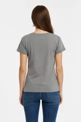 Remera negra de manga corta, con cuello redondo y ajuste al cuerpo. Cuenta con un gran estampado floral en tono gris en el frente y detalle de tachas plateadas alrededor del cuello y en los puños.