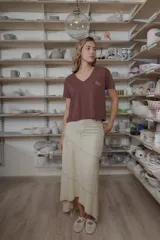 Remera negra de manga corta con escote en V, corte holgado y aberturas laterales en el dobladillo. Presenta un pequeño bordado en tono contrastante en el pecho con la inscripción "CRIADO".