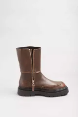 Bota de cuero marrón con caña media, puntera redondeada y suela track de goma negra.