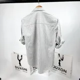 Camisa de manga larga a rayas verticales grises y blancas, con cuello italiano y logo bordado en el pecho.