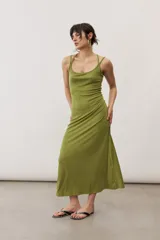 Vestido largo color verde suave, sin mangas, con escote redondo y silueta al cuerpo que se ensancha levemente hacia el dobladillo.