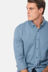 Camisa de manga larga color verde oscuro, con cuello abotonado y logo bordado en el pecho.