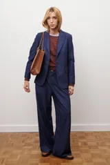 Pantalon de corte recto y pierna ancha, confeccionado en tejido tipo denim oscuro. Presenta tiro alto, cintura con cierre frontal y bolsillos laterales funcionales.