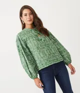 Blusa tipo bata de algodón con tejido laise bordado, cuello redondo con cordones y borlas, y mangas largas abullonadas con puños ajustados.
