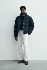 Campera puffer acolchada de corte regular fit, confeccionada en tejido técnico azul marino repelente al agua. Relleno interior de 80% plumón y 20% pluma. Cuenta con cuello subido, manga larga con puño elástico, bolsillos frontales de plastrón con solapa y cierre de cremallera oculta con solapa de botones a presión.