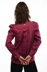 Camisa blanca de lino con cuello clásico, mangas largas con volumen y frunces en los hombros.