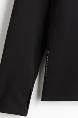 Remera deportiva negra de manga larga con cuello elevado y medio cierre frontal. Presenta mangas raglán superlargas con abertura para el pulgar.