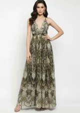 Vestido largo de fiesta confeccionado en tela mesh con acabado glitter. Presenta un diseño con escote en V profundo, breteles finos y falda amplia con caída fluida.