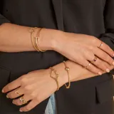Pulsera de malla metálica con dije central en forma de corazón, ambos en acabado dorado.