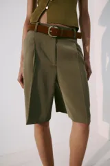 Bermuda fluida color verde militar con pinzas delanteras, tiro medio y trabillas en la cintura. Incluye un cinturón marrón de gamuza con hebilla metálica dorada.