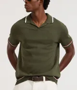Camisa polo de manga corta color verde oliva, confeccionada en tejido de punto, con cuello y puños con ribetes contrastantes en blanco y rojo.
