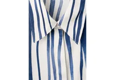 Camisa de poliéster con estampado de rayas verticales en tonos azul y blanco, cuello camisero, mangas largas y cierre frontal con botones.