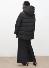 Campera acolchada tipo puffer color negro, con capucha, cuello alto y cierre frontal de cremallera doble. Presenta diseño recto, mangas largas con puños elásticos y bolsillos laterales con cierre.