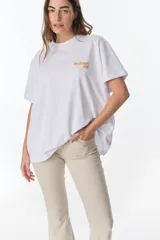 Remera blanca de algodón con cuello redondo, mangas cortas y un estampado frontal que dice "The flowers Club" en color naranja.