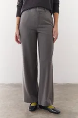 Pantalón de vestir gris de corte recto y pierna ancha, con cintura alta, bolsillos laterales y cierre frontal.
