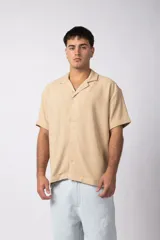 Camisa de manga corta color beige, con cuello cubano y textura entramada. Corte relajado.