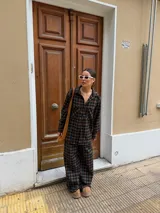 Pantalón de corte recto y holgado, confeccionado en tela de viyela con estampado de cuadros en tonos negro, gris y blanco. Presenta cintura elástica para mayor comodidad.